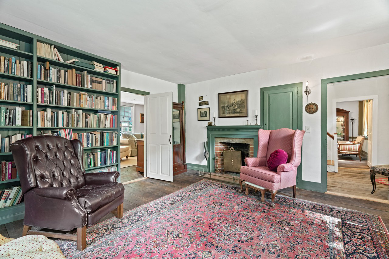 The library with built-in bookcases shares one of the many fireplaces in this center chimney home.