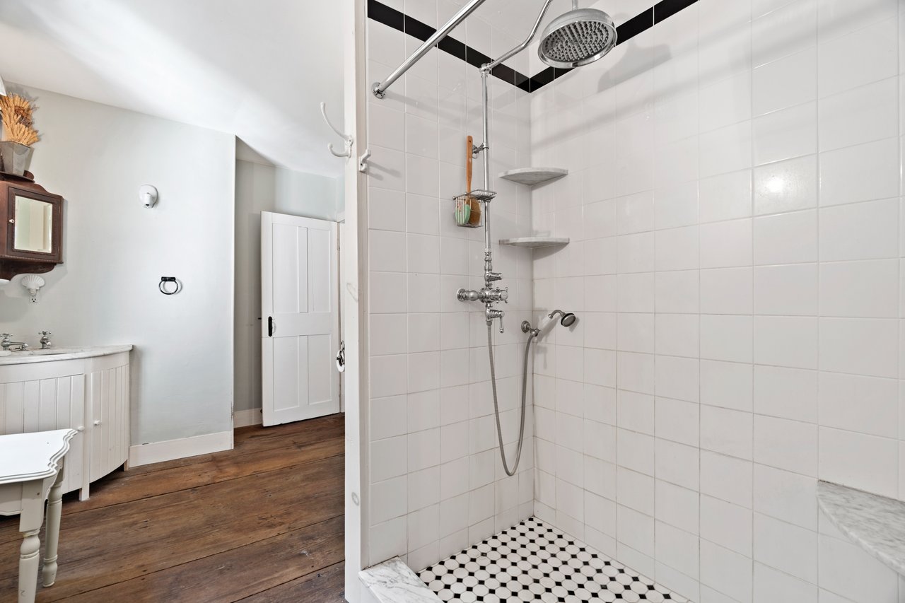 The guest bathroom has a walk in shower featuring with ceramic tile and chrome fixtures.