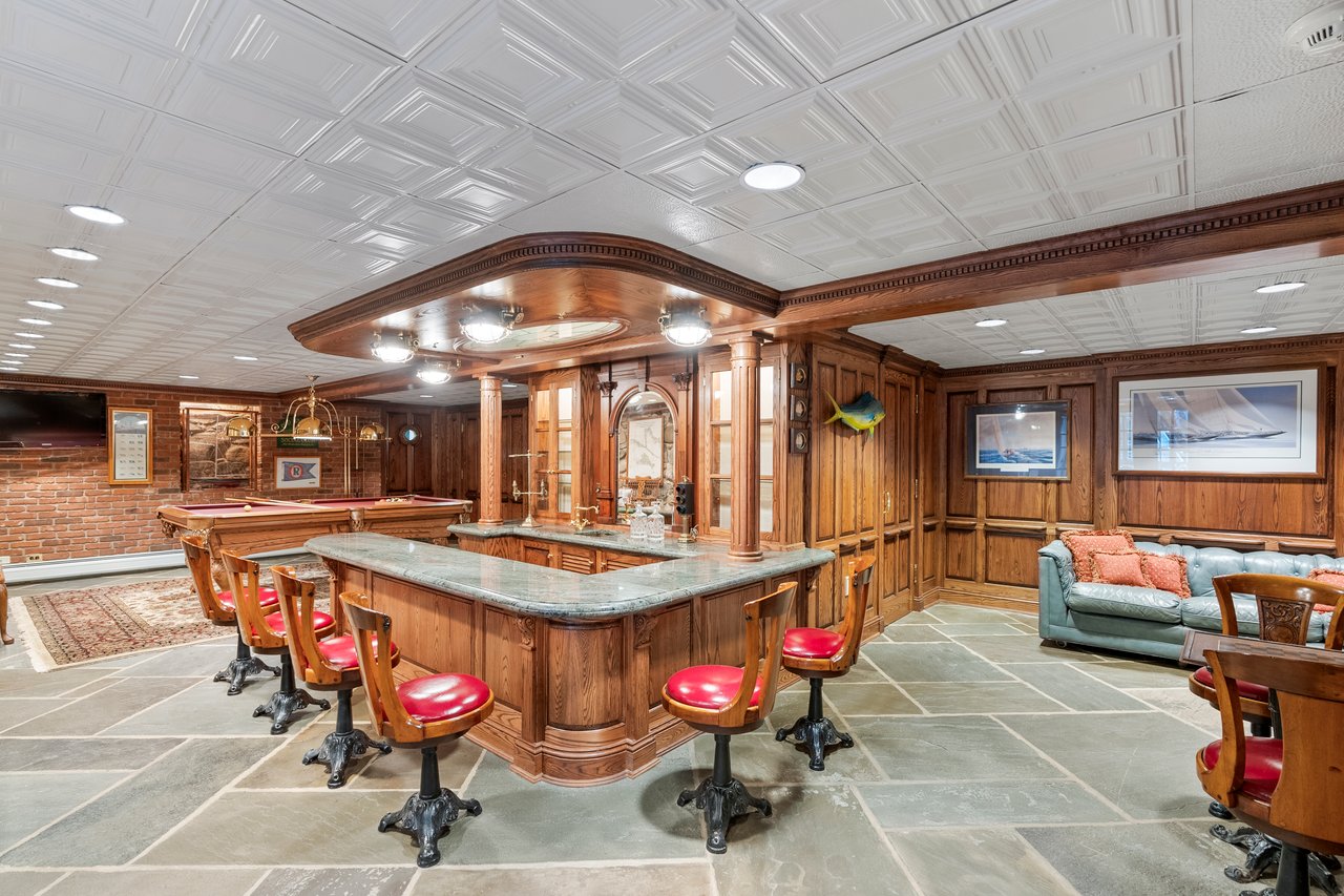 Lower level boasts a beautifully finished bar area complete w antique stools that add a touch of timeless charm