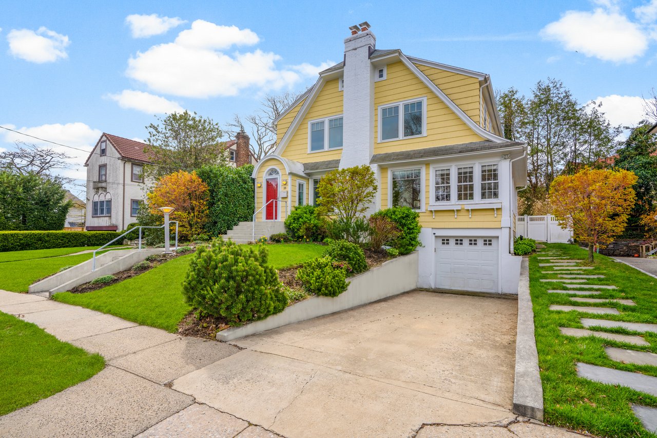 View of front of property featuring a chimney, concrete driveway, fence, a garage, and a front yard