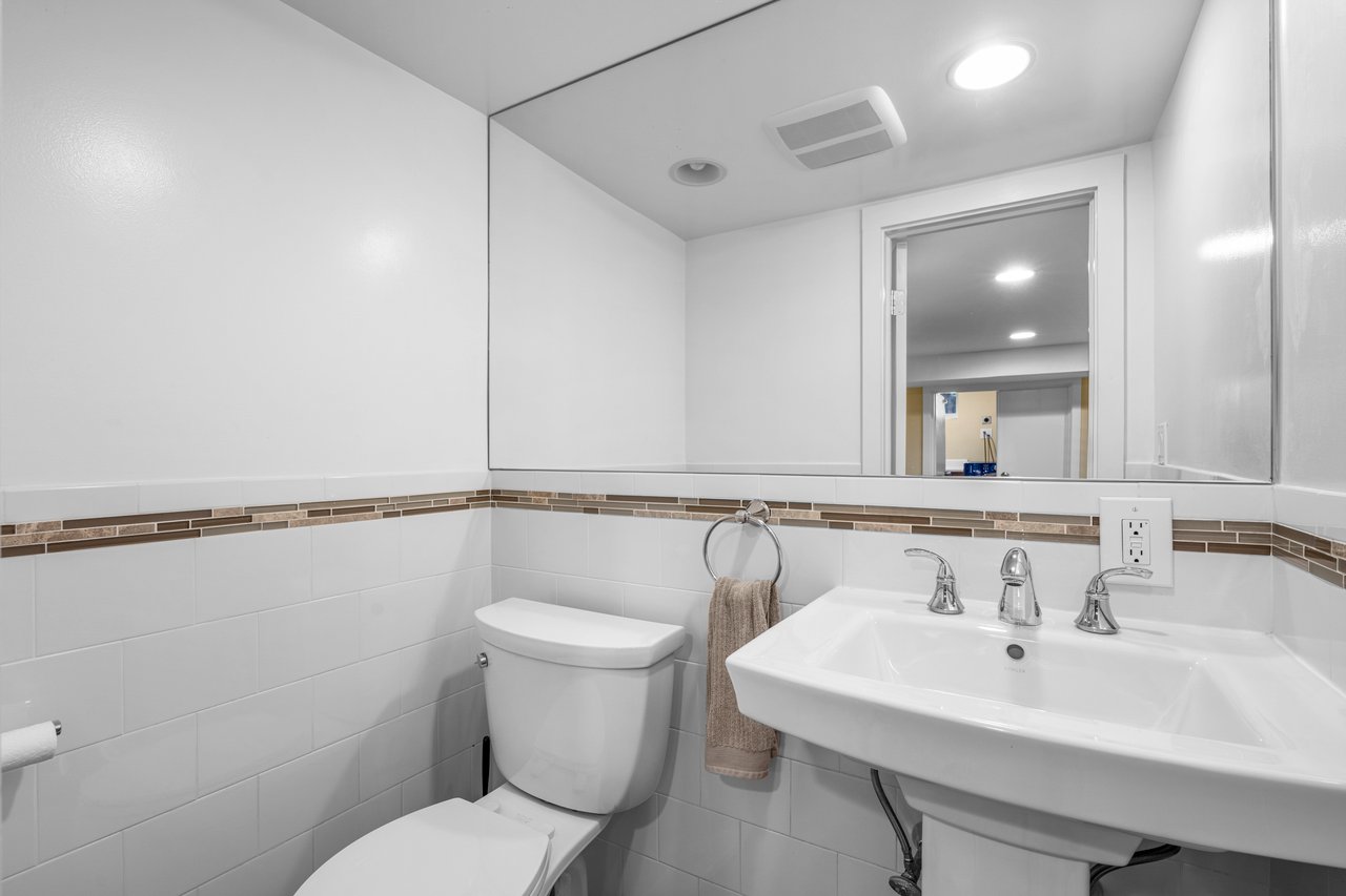 Bathroom featuring a sink, tile walls, toilet, visible vents, and recessed lighting