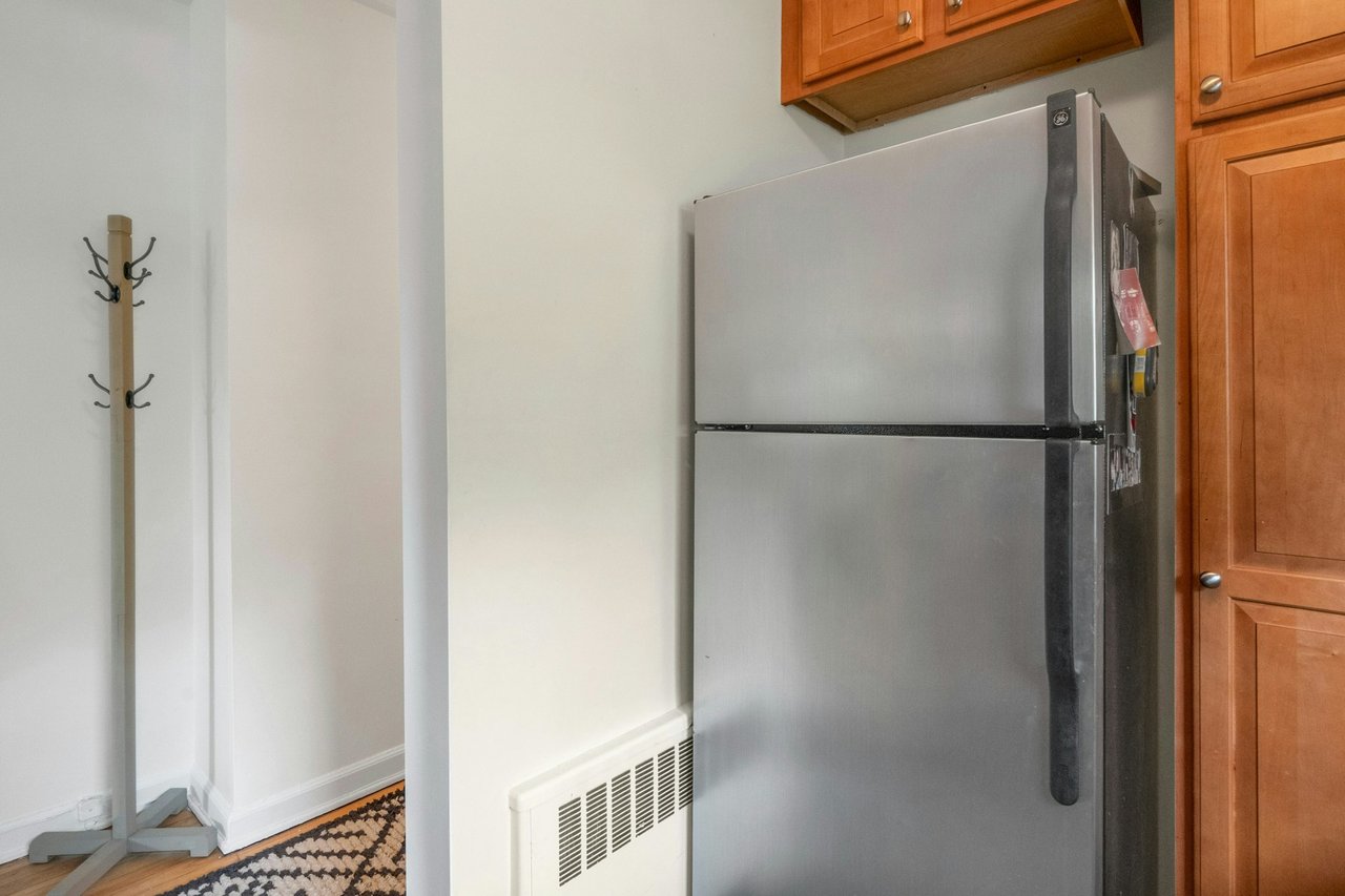 Kitchen with freestanding refrigerator, visible vents, baseboards, and brown cabinets