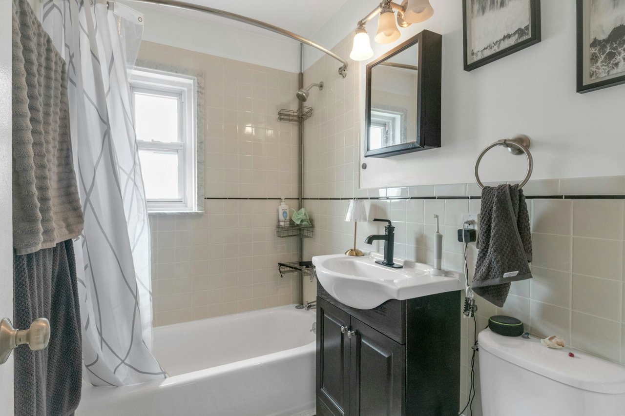 Bathroom with toilet, tile walls, vanity, wainscoting, and shower / tub combo