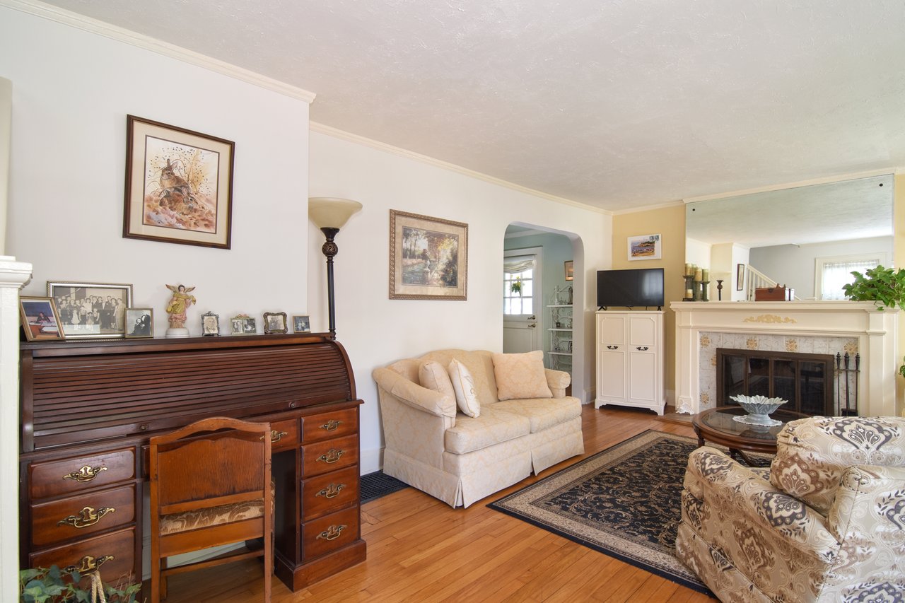 Step into a bright and inviting living room featuring original hardwood floors, elegant arched walkways, detailed crown molding, and an abundance of natural light....