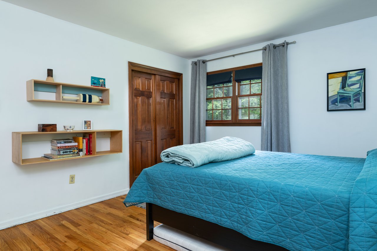 Bedroom with wood finished floors, a closet, and baseboards
