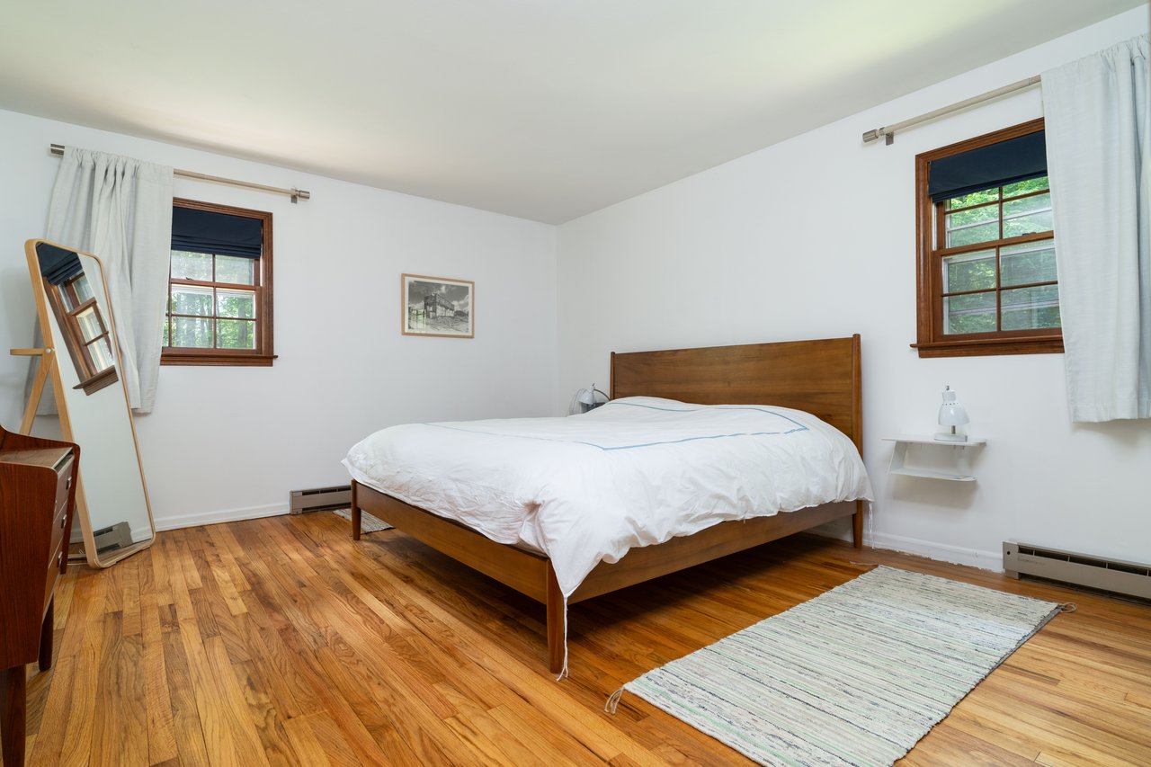 Primary Bedroom with a baseboard heating unit, multiple windows, and light wood-style flooring