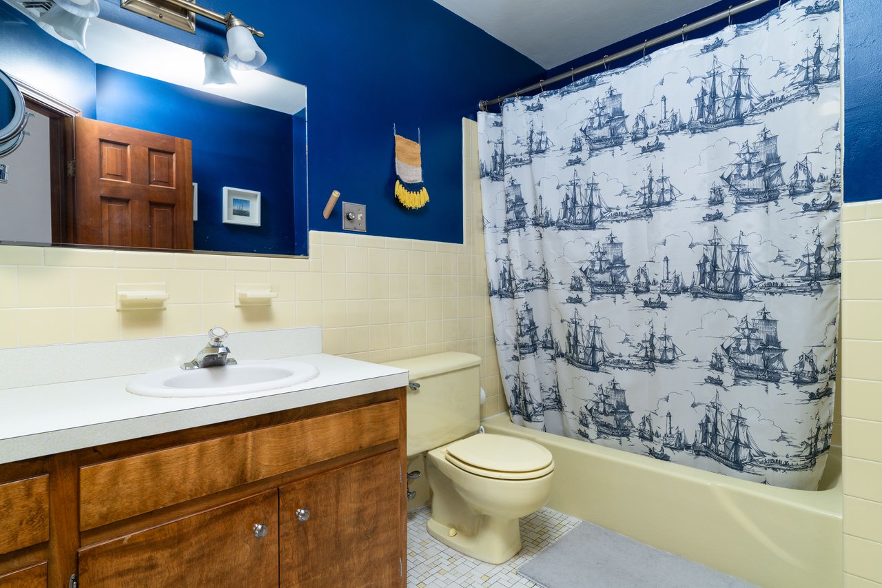 Hall Full bath with tile walls, vanity, toilet, shower / tub combo, and tile patterned floors