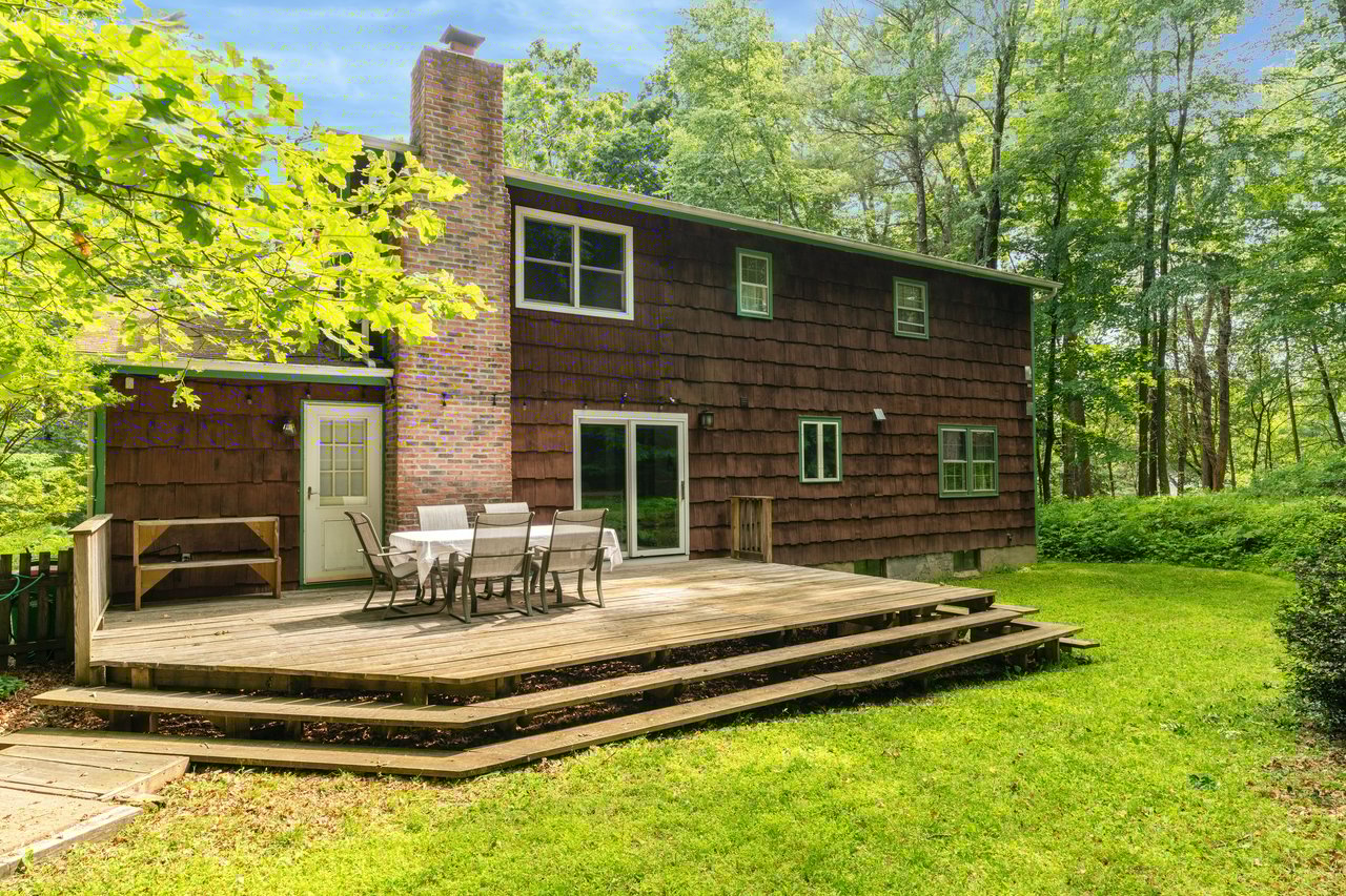 Rear view of property with a chimney, a yard, a wooden deck, and outdoor dining space
