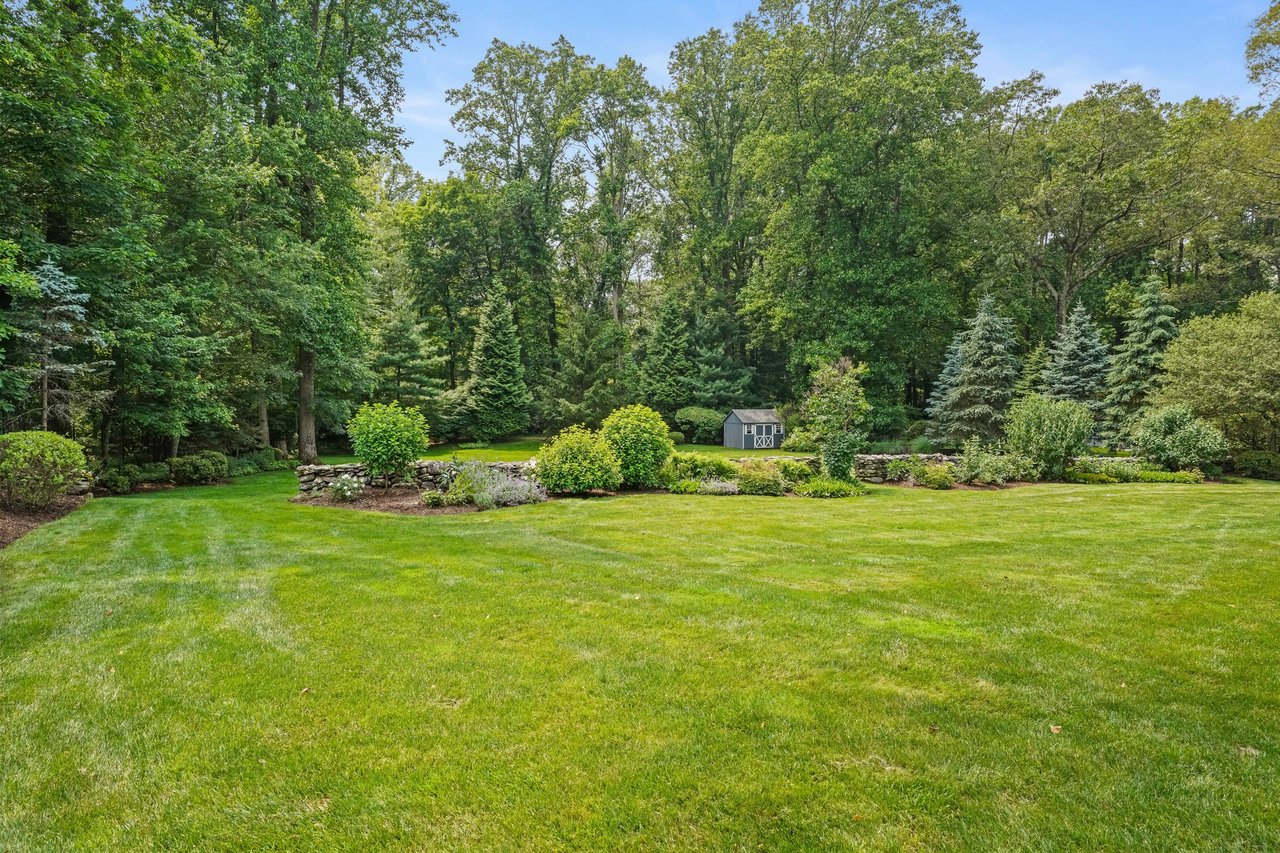 Sweeping views of the sprawling lawn, accented with lovely stone wall