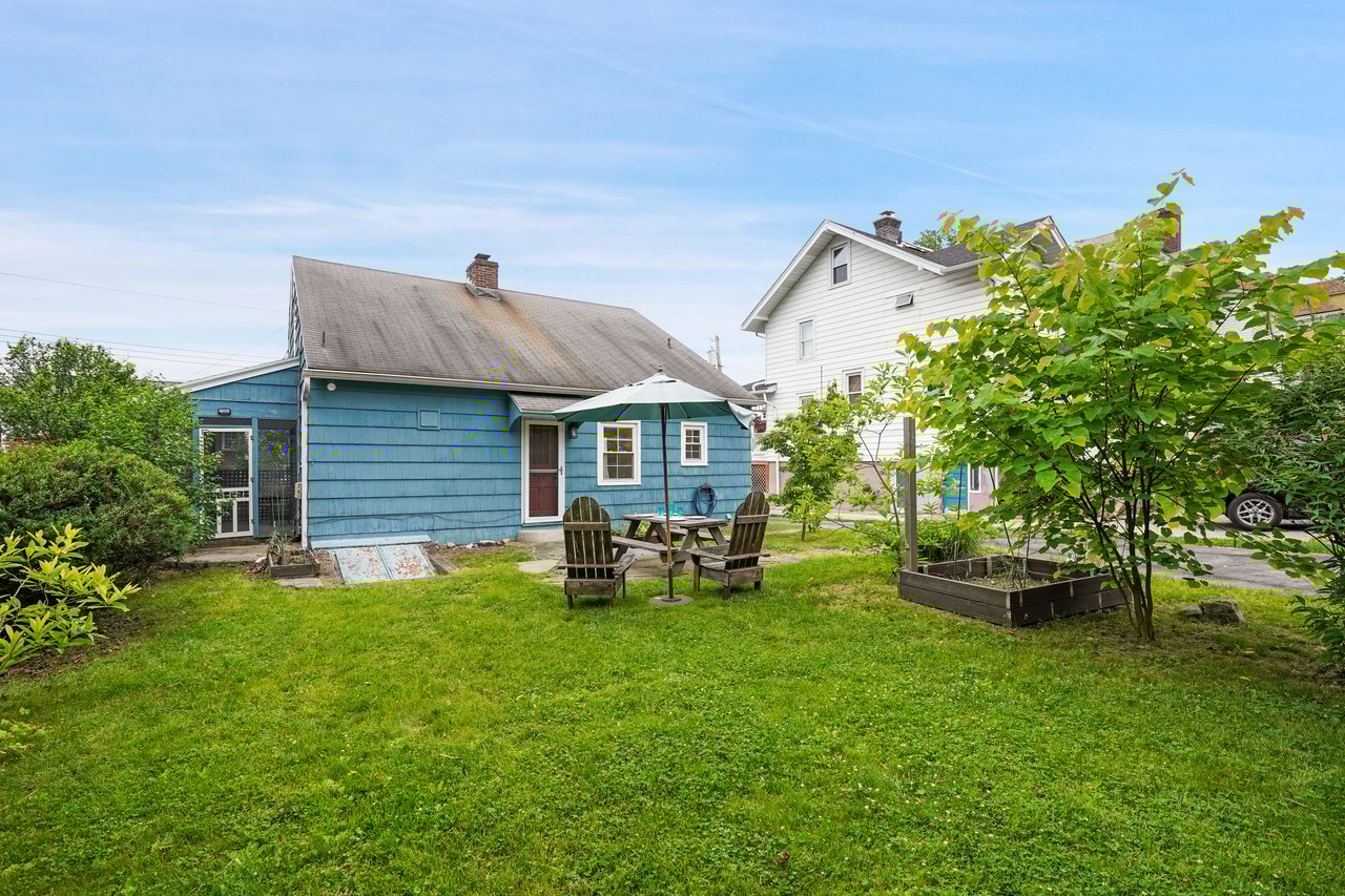 Rear view of house featuring a garden, a lawn, and patio