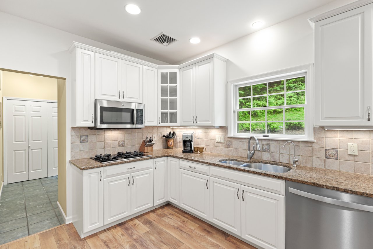 Kitchen with appliances with stainless steel finishes, light stone countertops, glass insert cabinets, white cabinetry, and recessed lighting