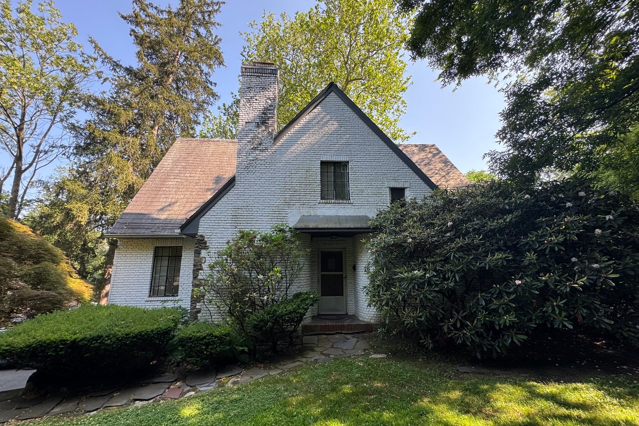 Tudor home featuring a front yard, a chimney, and brick siding