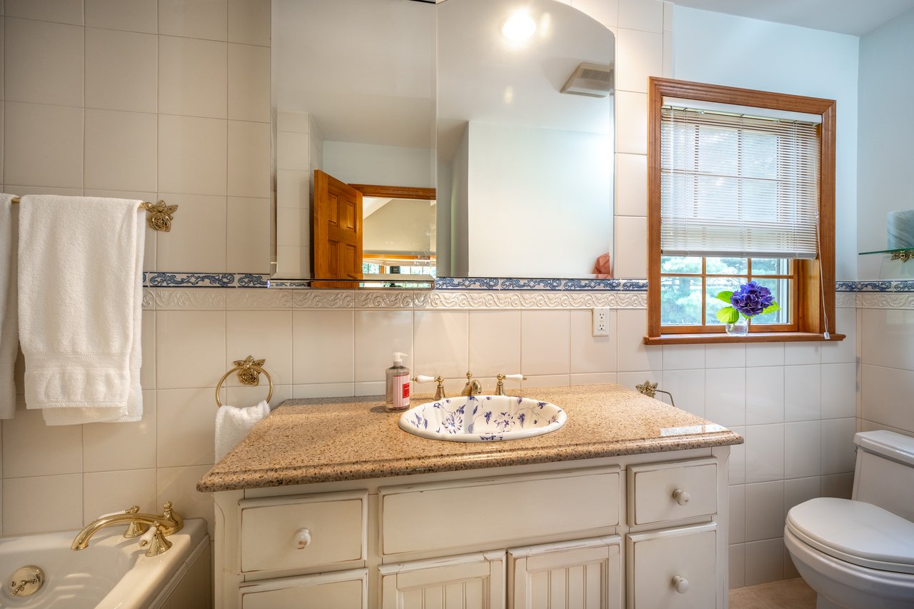 Full bathroom with tile walls, vanity, and a bath.