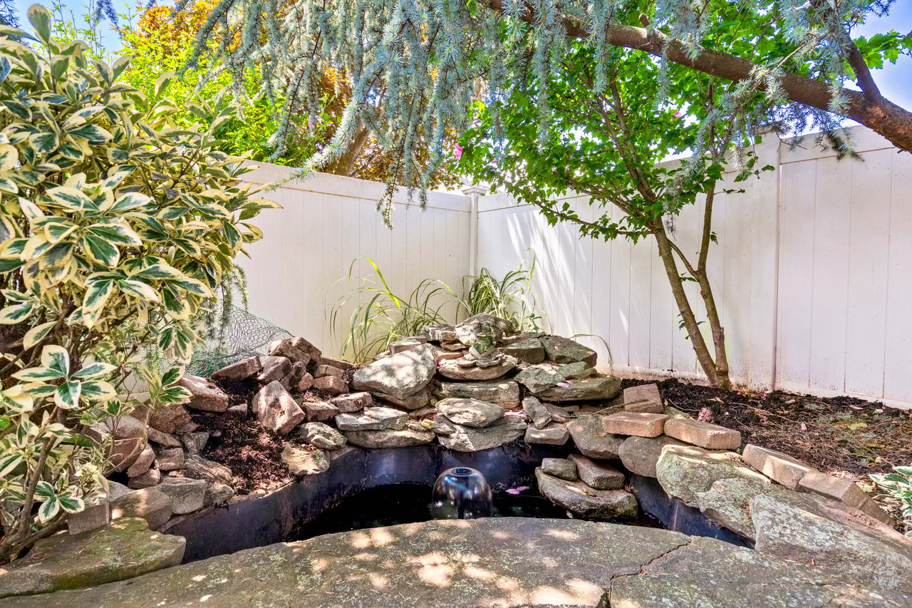 The backyard has shade from mature trees and a waterfall