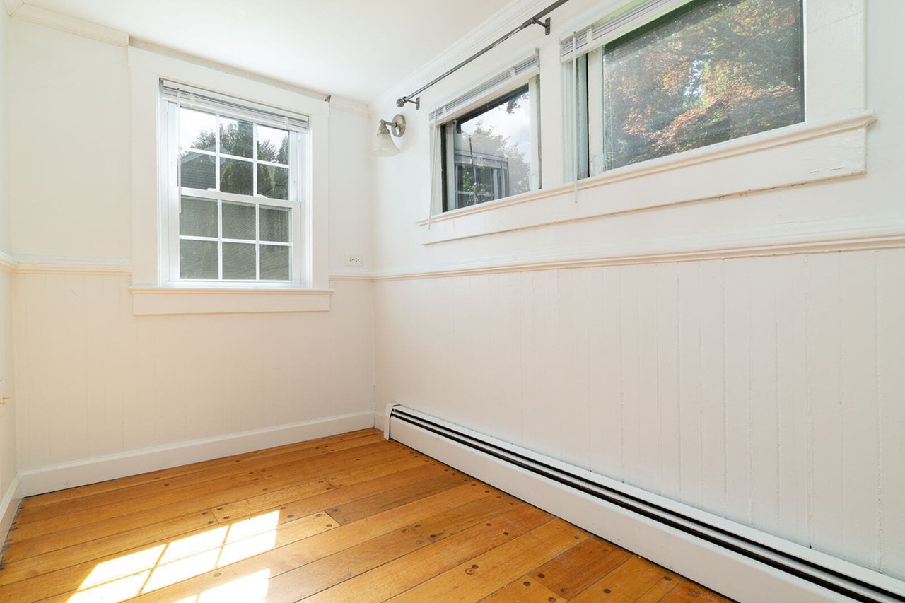 Unfurnished room with a baseboard heating unit, hardwood / wood-style flooring, and a wainscoted wall