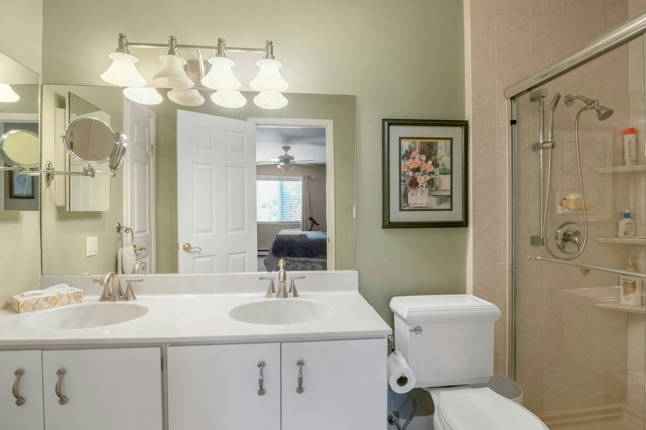 updated primary bathroom, double vanity, a shower stall and a linen closet