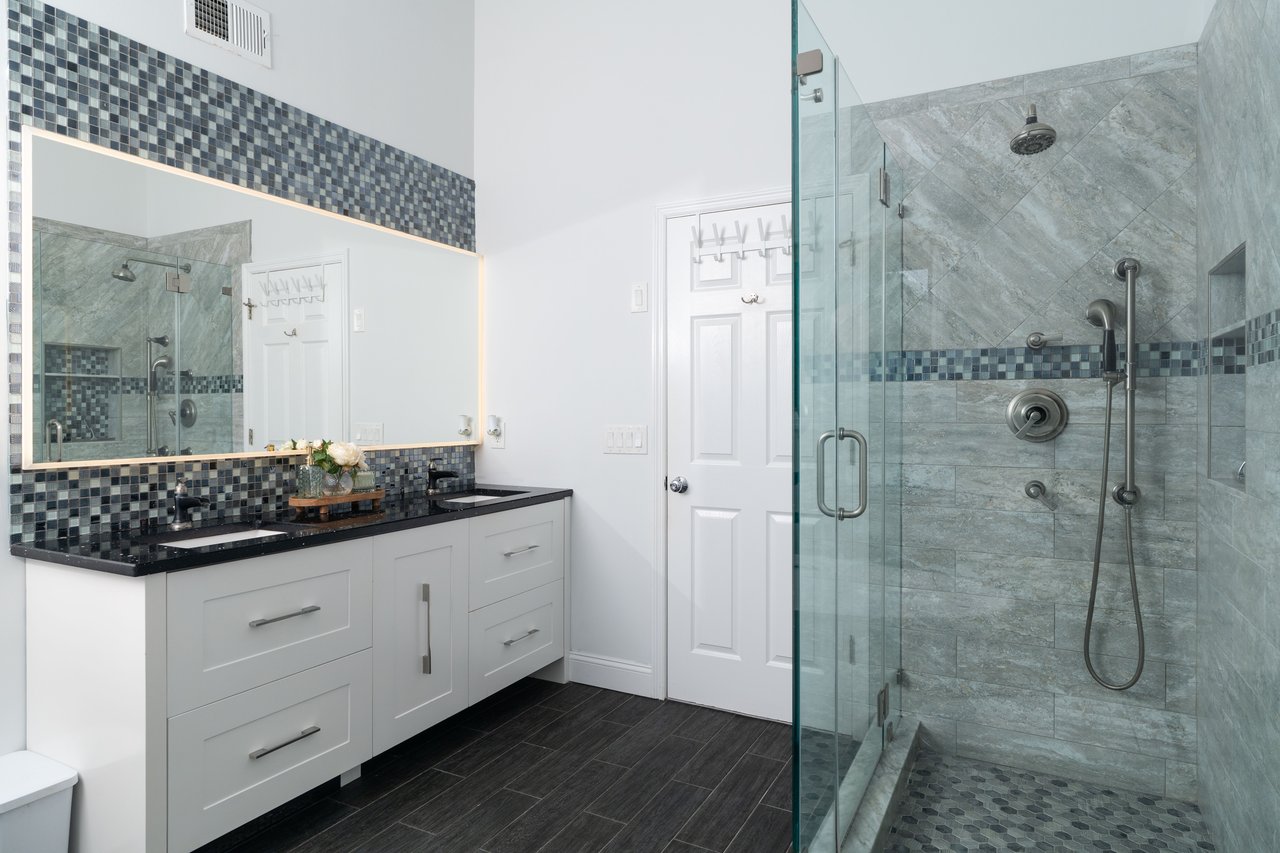 Full bath with a shower stall, double vanity, backsplash, and wood finish floors