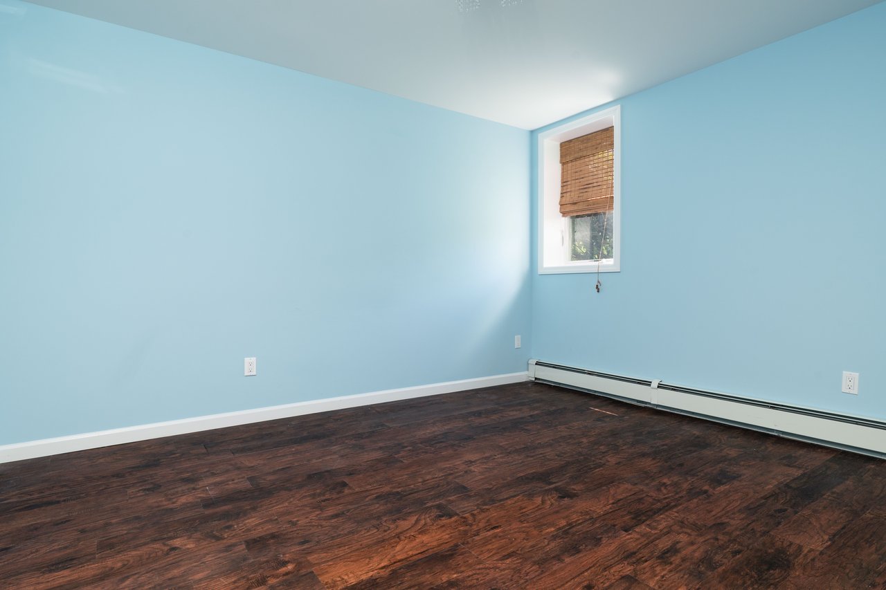 Basement bedroom room with dark wood-style floors and baseboard heating