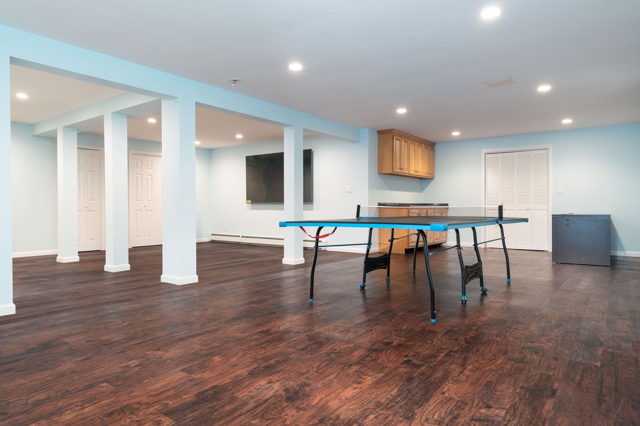 Recreation room with wood-style floors recessed lighting, and baseboard heating