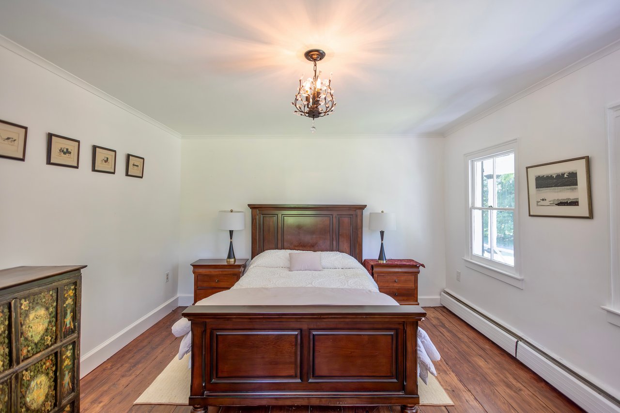 Bedroom featuring a baseboard radiator, dark wood-type flooring, crown molding, and a chandelier
