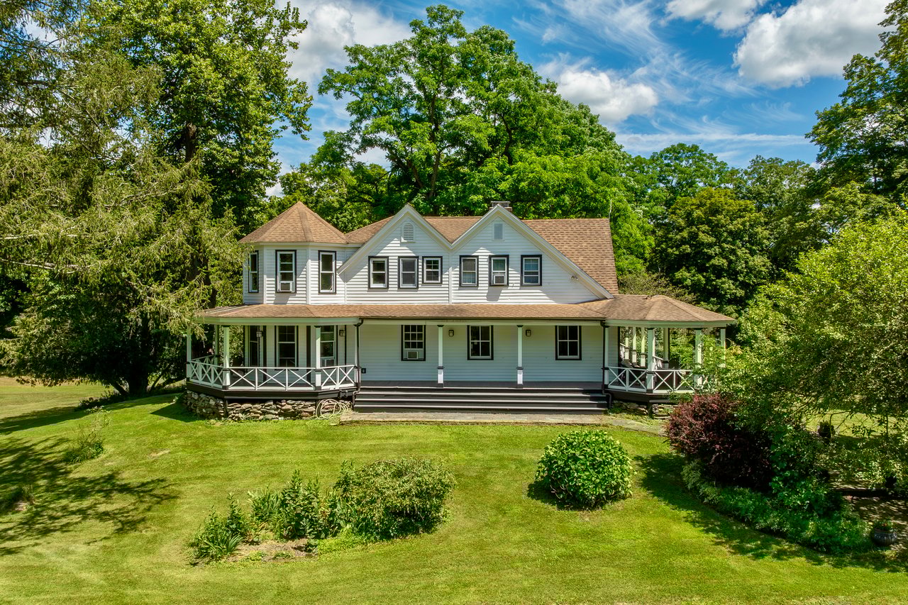 View of front of house with a shingled roof, a front lawn, and covered porch