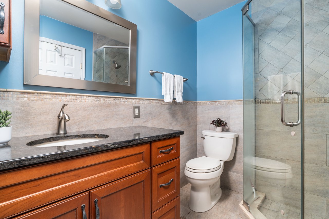 Bathroom featuring vanity, tile walls, a shower stall, tile patterned floors, and wainscoting