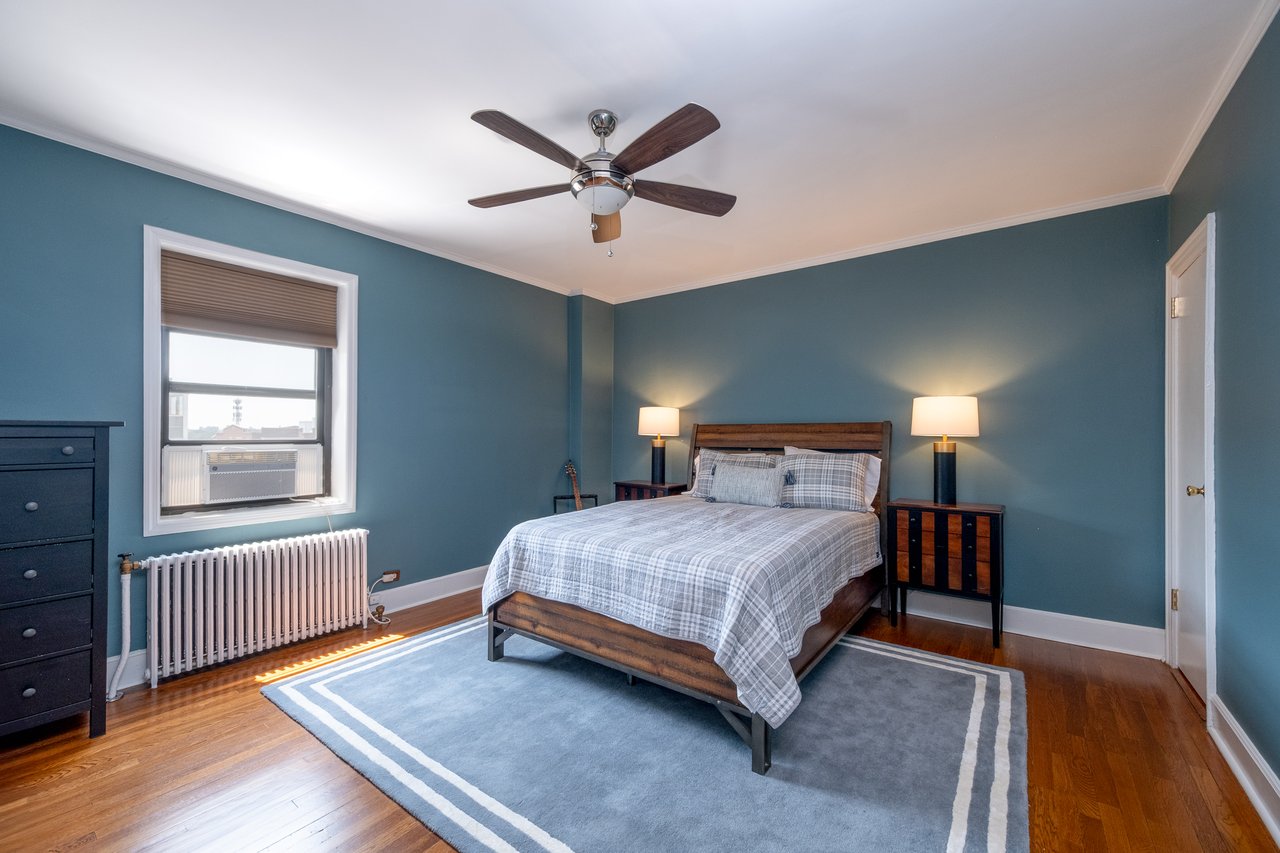 Primary Bedroom with radiator, wood finished floors, crown molding, and ceiling fan