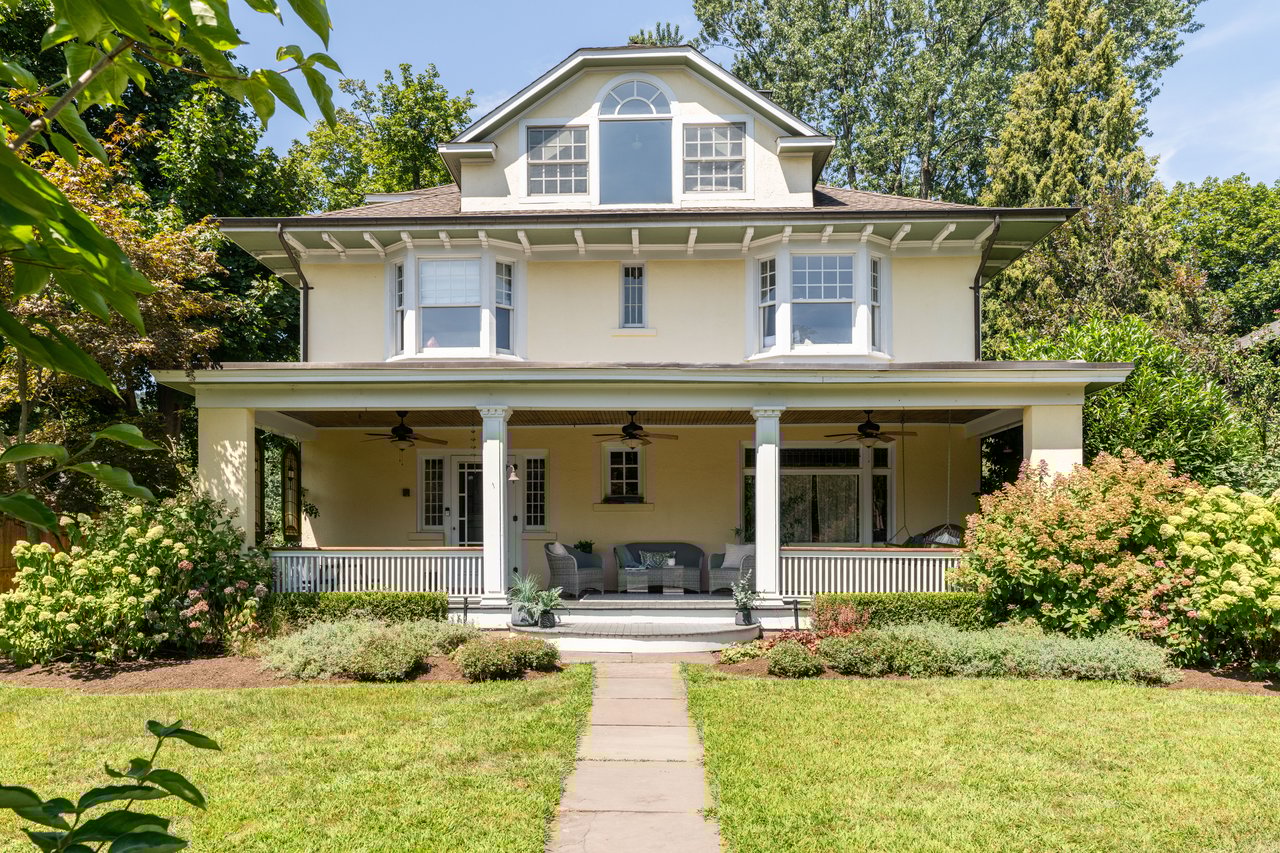 American foursquare style home with a ceiling fan, stucco siding, covered porch, a front lawn.