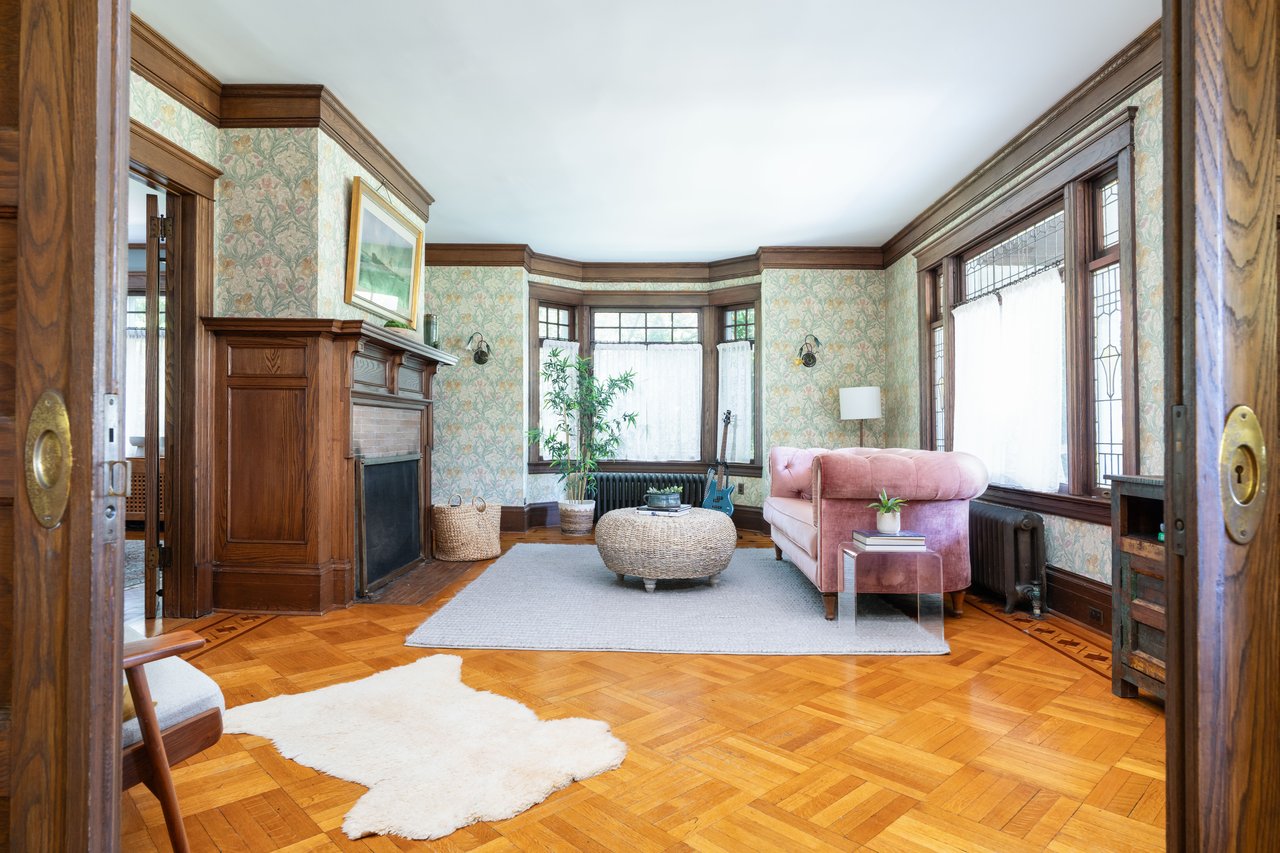 Living room featuring wallpapered walls, radiator, ornamental molding, and a fireplace