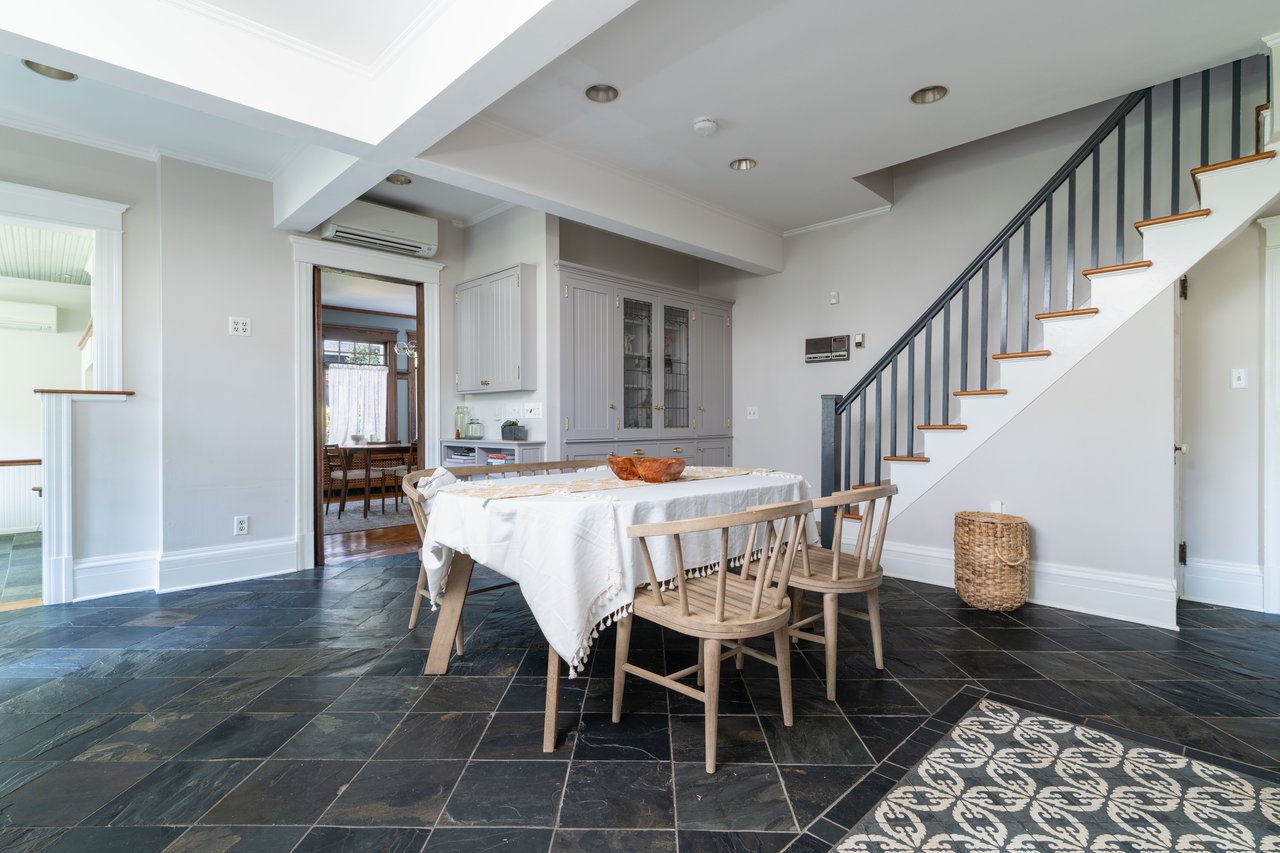 Dining area featuring beamed ceiling, stone tile flooring, ornamental molding, stairs, and a wall mounted air conditioner
