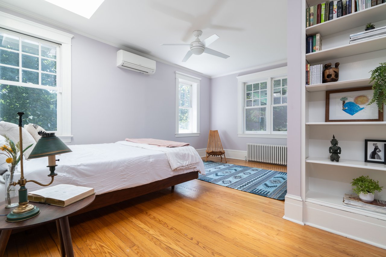Bedroom with crown molding, radiator heating unit, light wood-type flooring, ceiling fan, and an AC wall unit