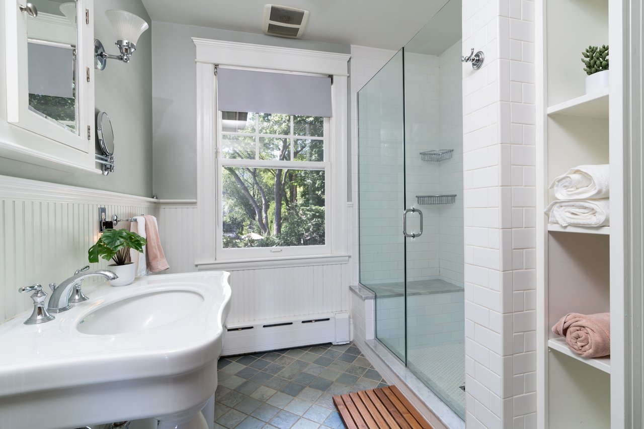 Bathroom featuring a shower stall, baseboard heating, and a wainscoted wall