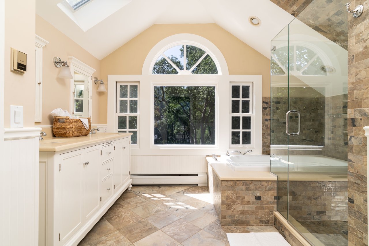 Bathroom featuring healthy amount of natural light, double vanity, lofted ceiling, and a shower stall
