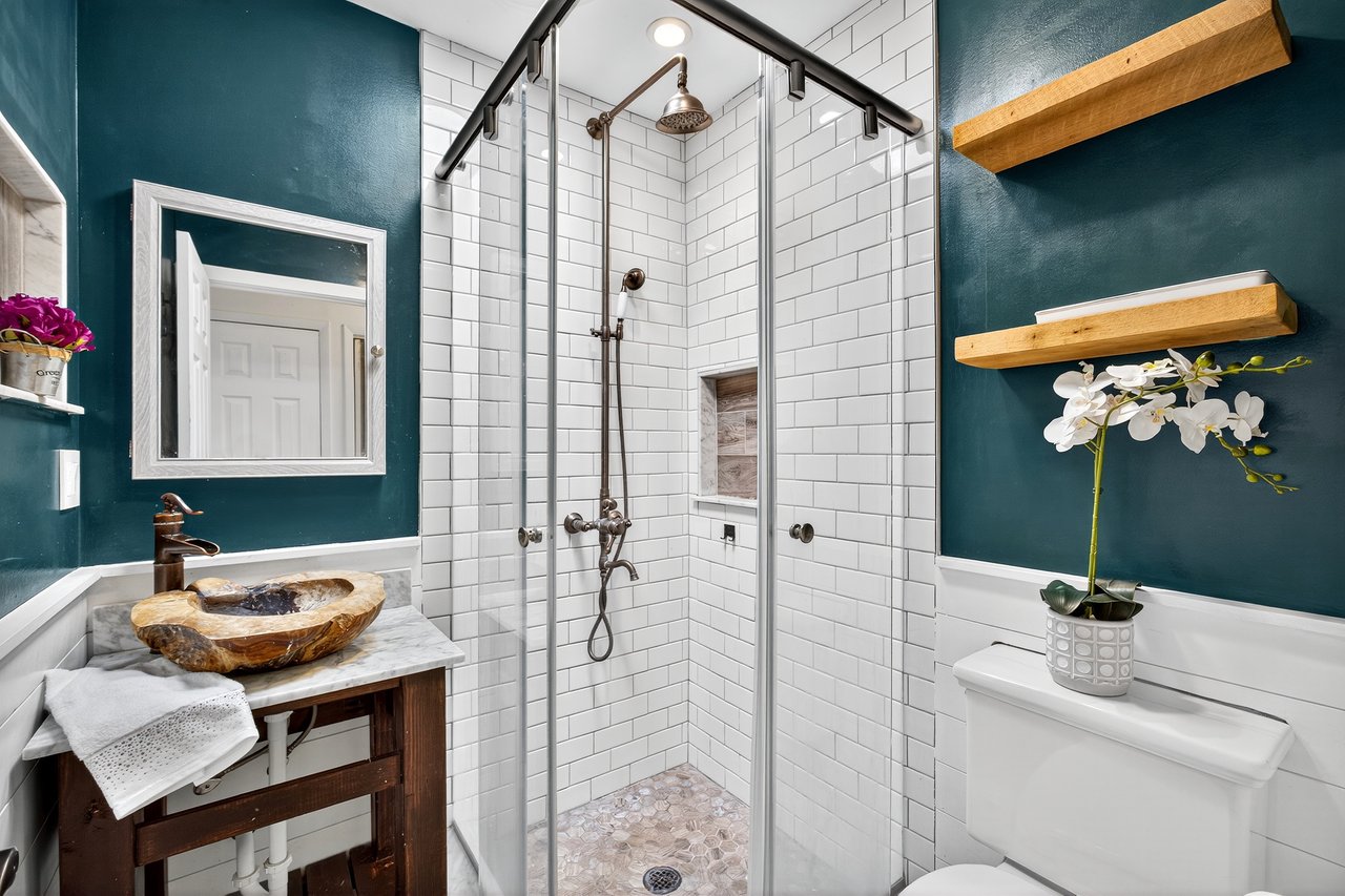Full bathroom featuring a shower stall, vanity, and a wainscoted wall
