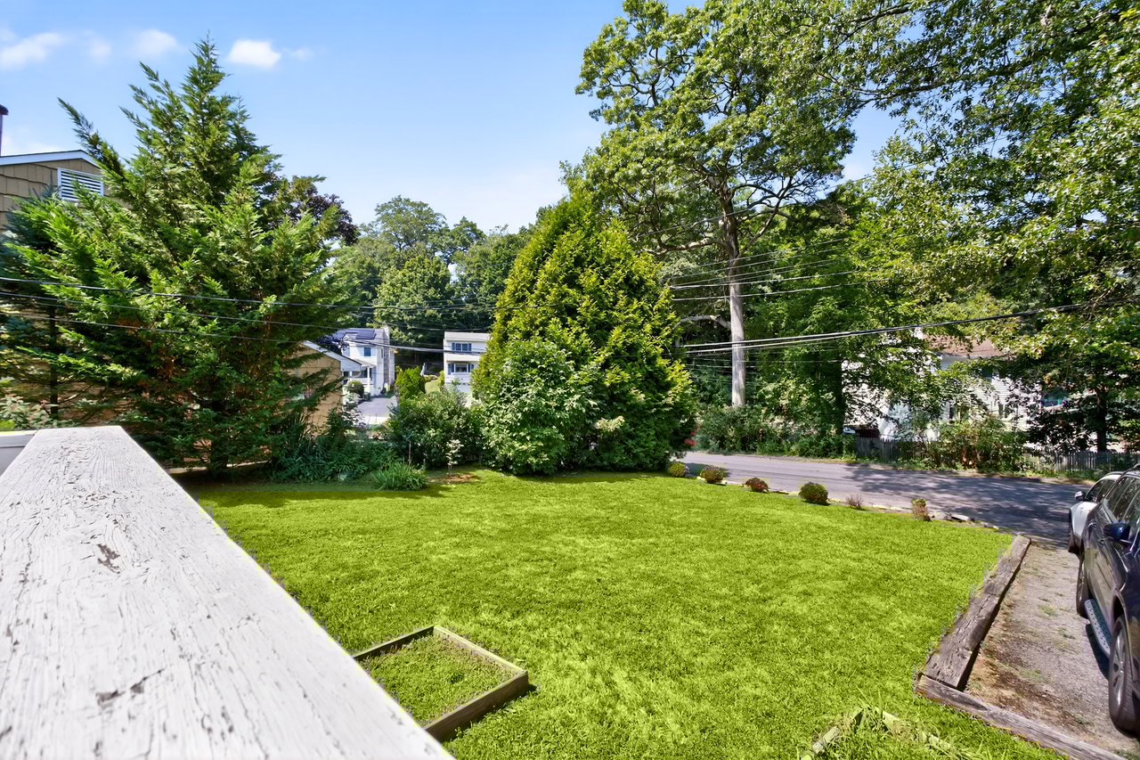 View of grassy yard with view of secluded wooded area