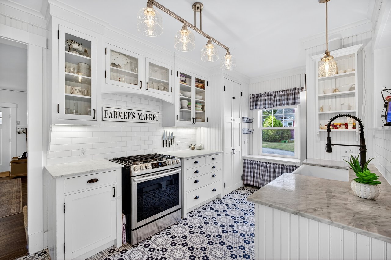 Kitchen featuring white cabinets, subway tile backsplash, stainless steel gas stove, marble counters, and crown molding