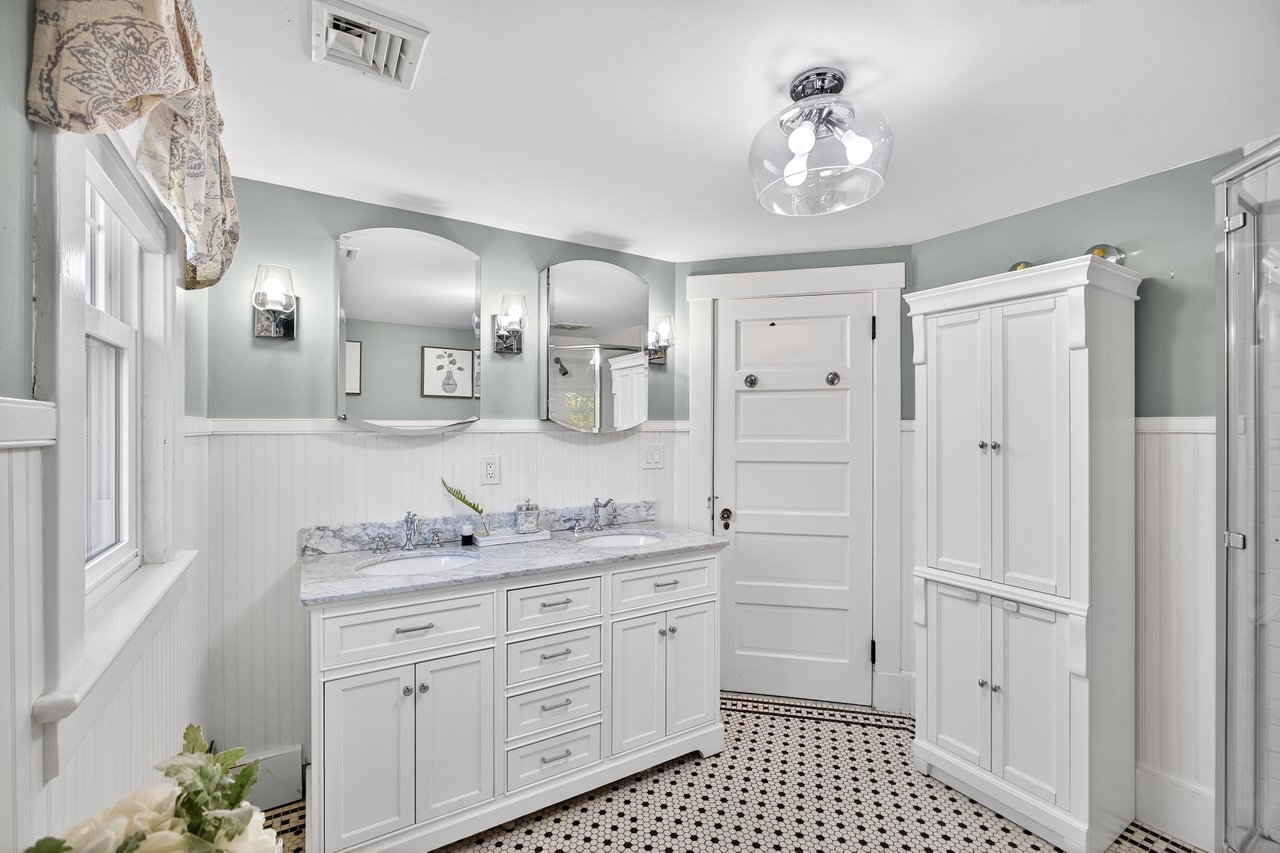 Bathroom featuring a wainscoted wall, double vanity, and a stall shower