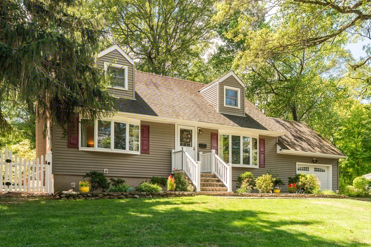 Cape cod house featuring fenced in yard, garden and one car garage