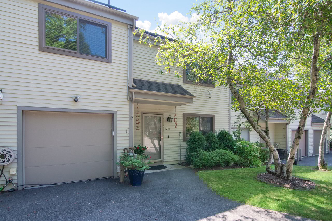 Traditional home featuring an attached garage, driveway, and a front lawn.