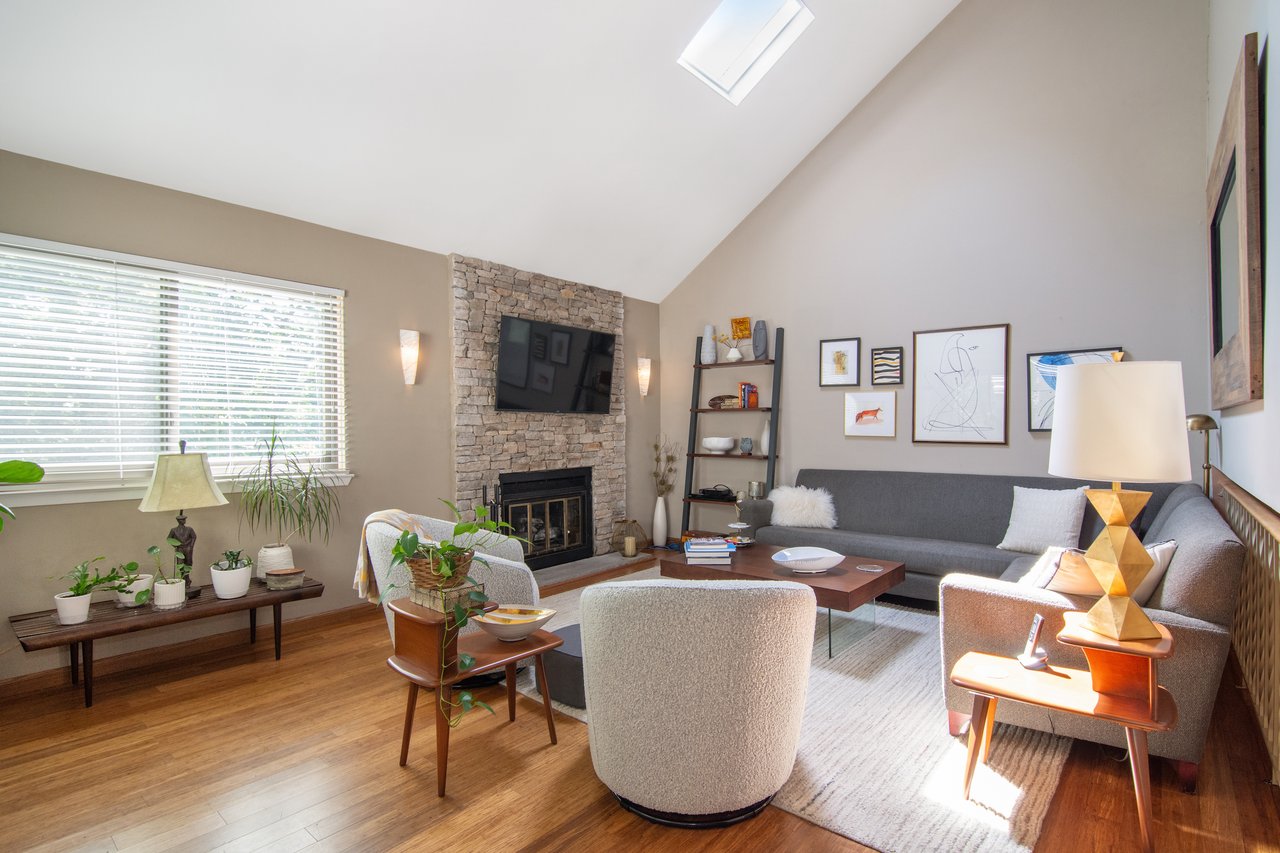 Living area featuring high vaulted ceiling, a skylight, wood finished floors, and a fireplace....