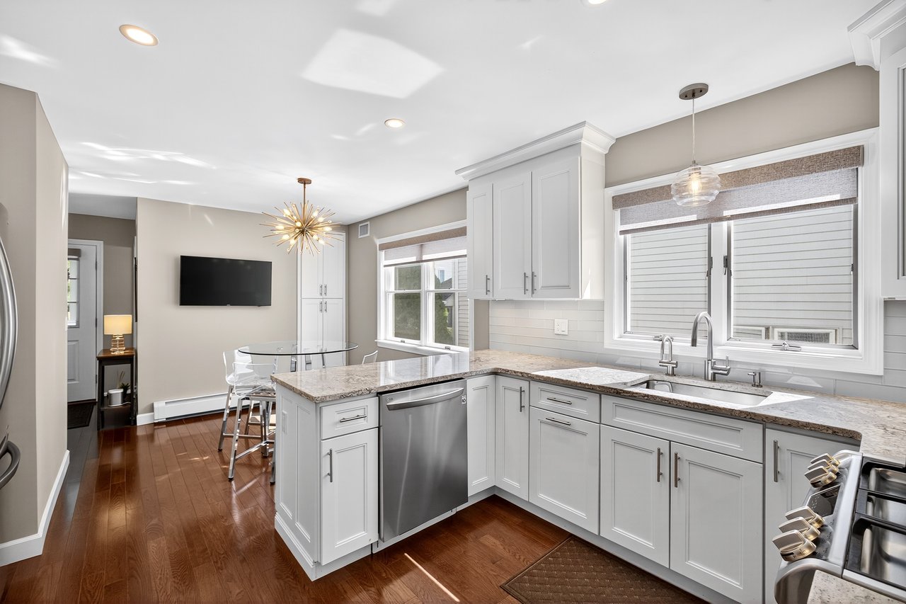 Kitchen with pendant lighting, quartzite, white cabinets, dark wood-hardwood flooring, and backsplash.