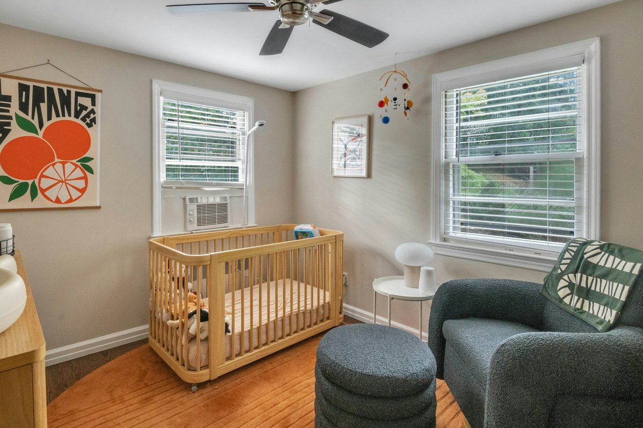 3rd. Bedroom with multiple windows, wood finished floors, and a crib