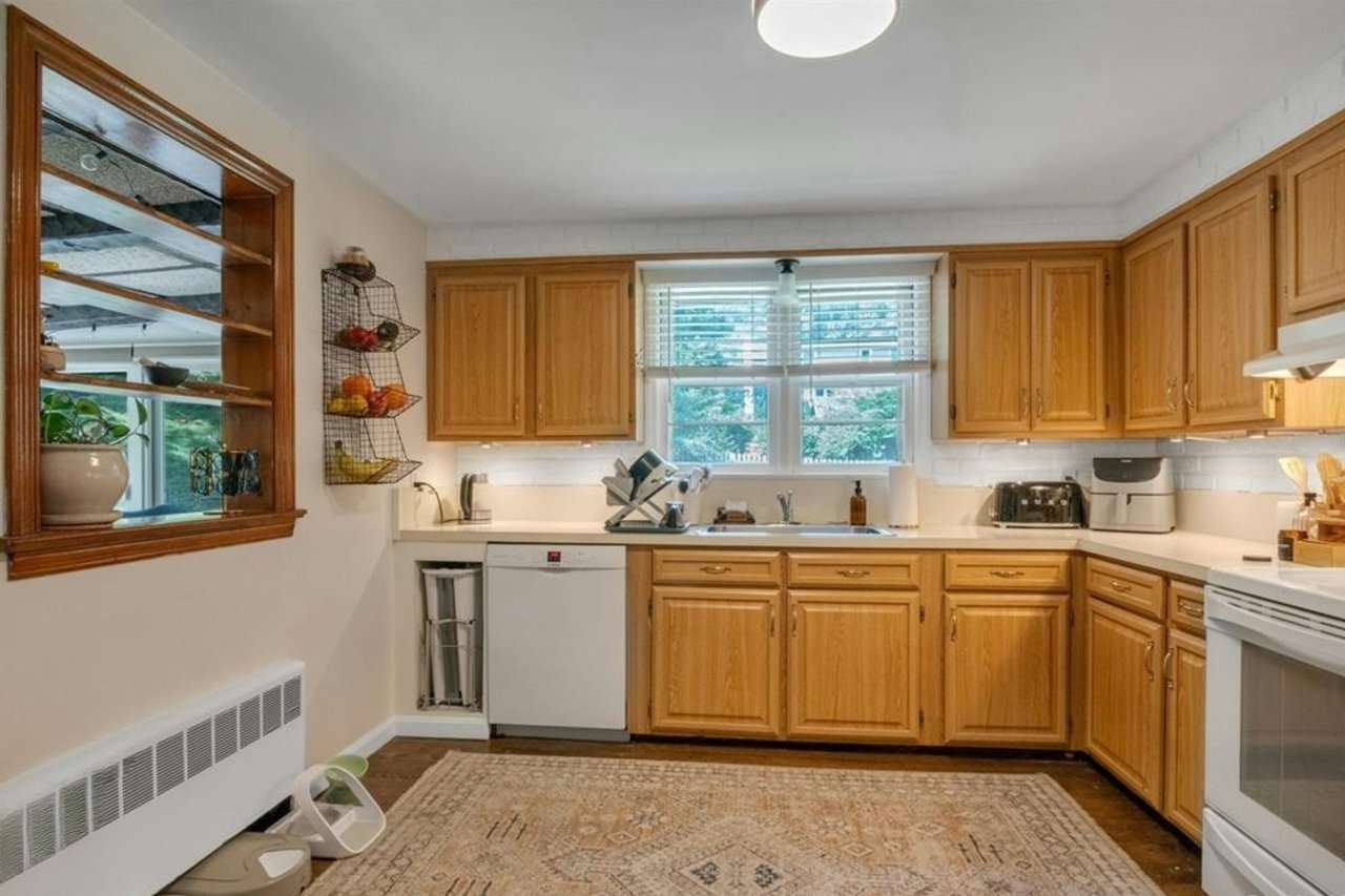 Kitchen featuring white appliances, dark wood-style flooring, under cabinet range hood, and light countertops