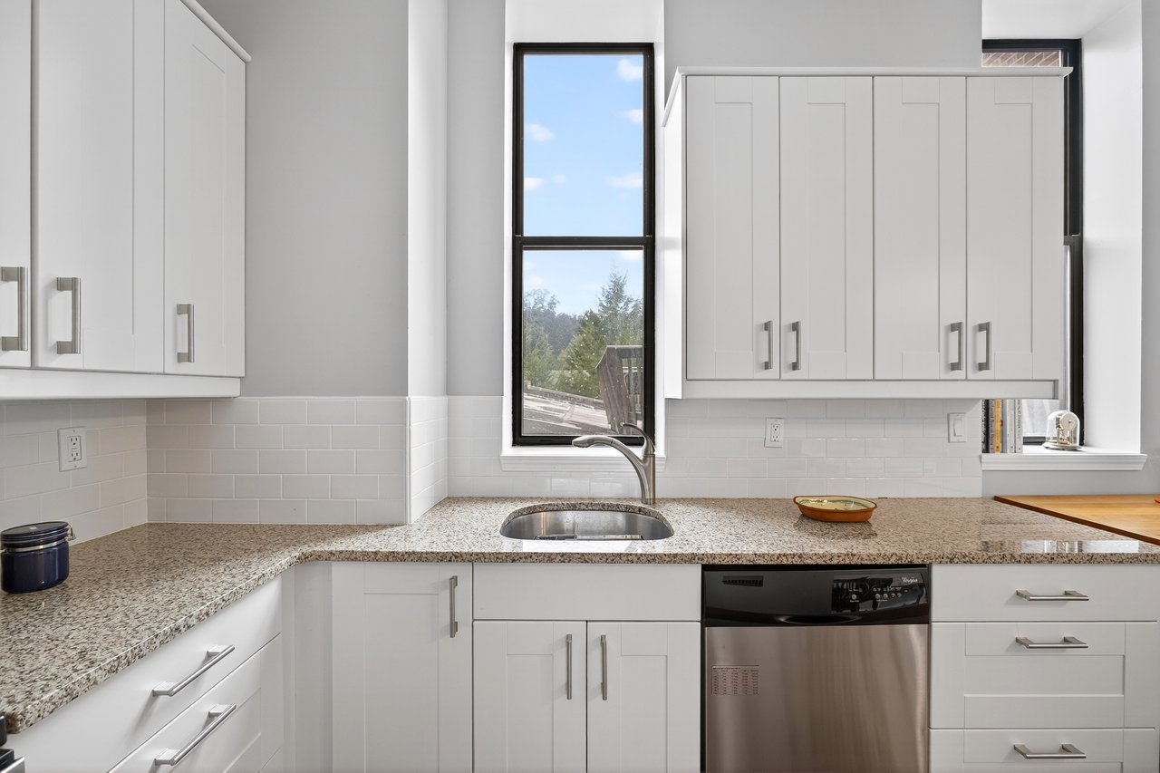 Kitchen featuring white cabinets, dishwasher, and light stone countertops...
