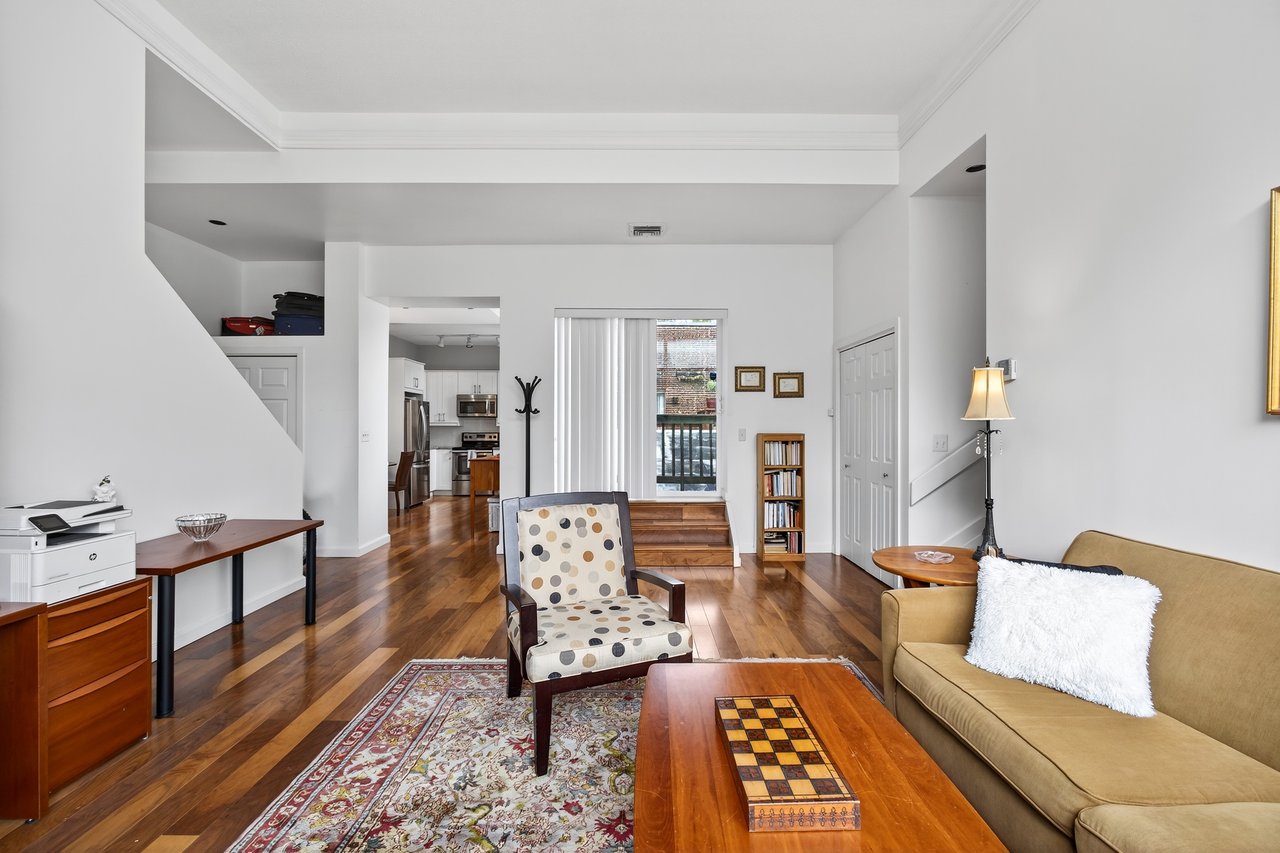 Living room featuring dark wood-style flooring and crown molding...