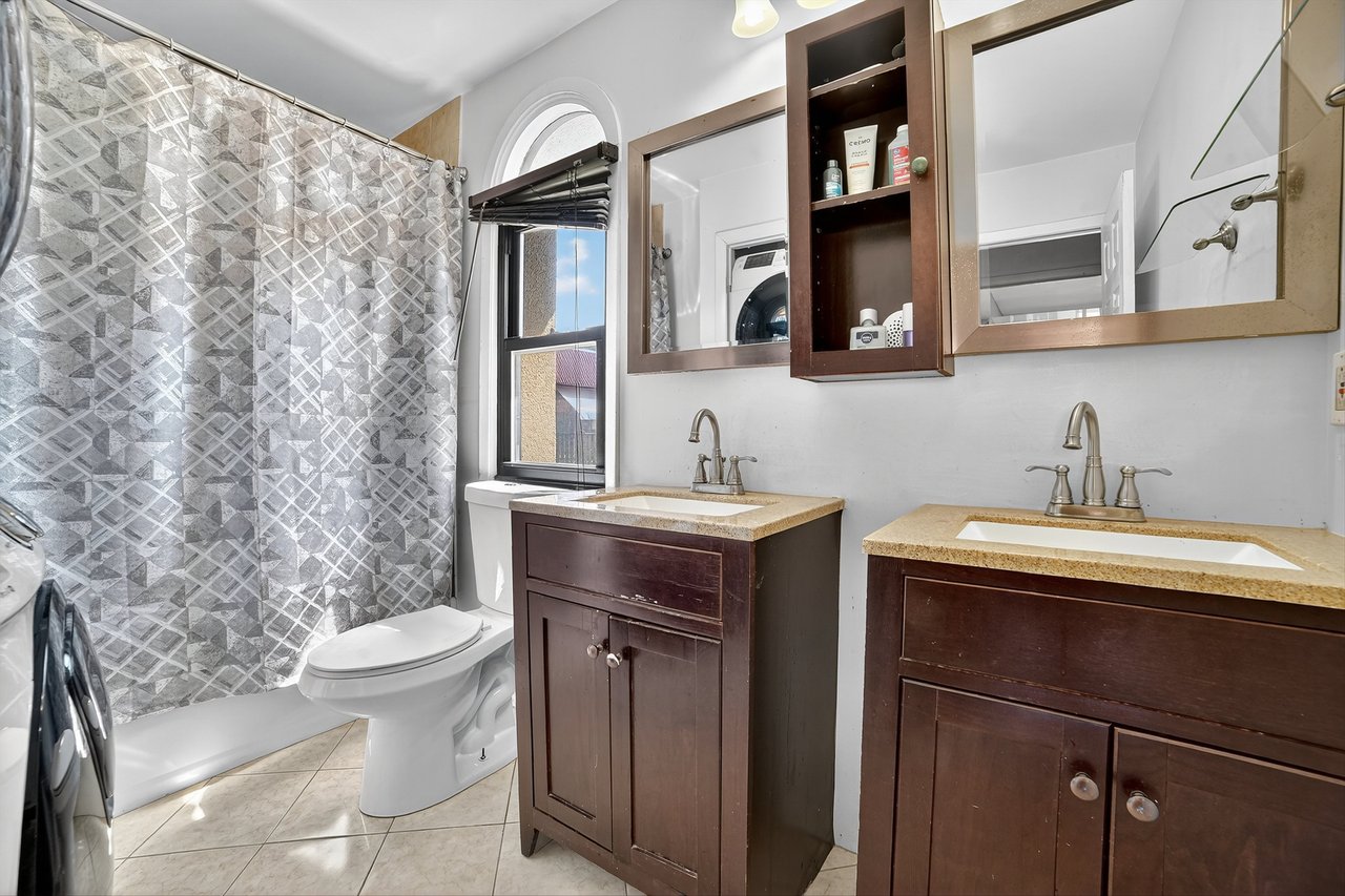 Bathroom with two vanities, light tile patterned floors, and washer / clothes dryer