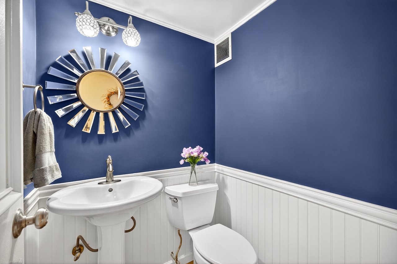 Half bathroom featuring a wainscoted wall and crown molding