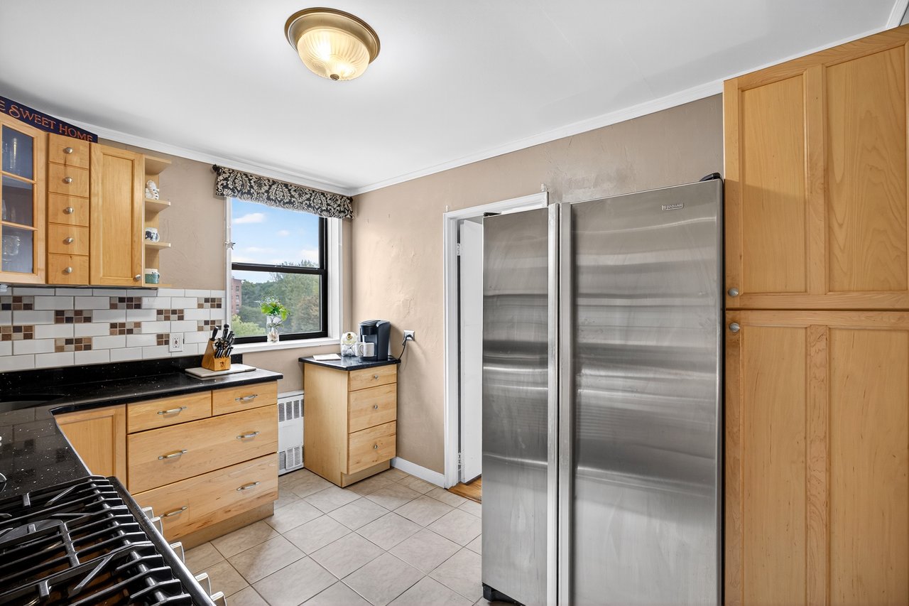 Kitchen with freestanding refrigerator, backsplash, light tile patterned floors, radiator, and open shelves
