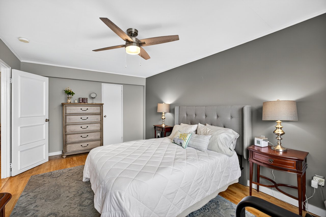 Bedroom with light wood finished floors, crown molding, a ceiling fan, and a walk in closet