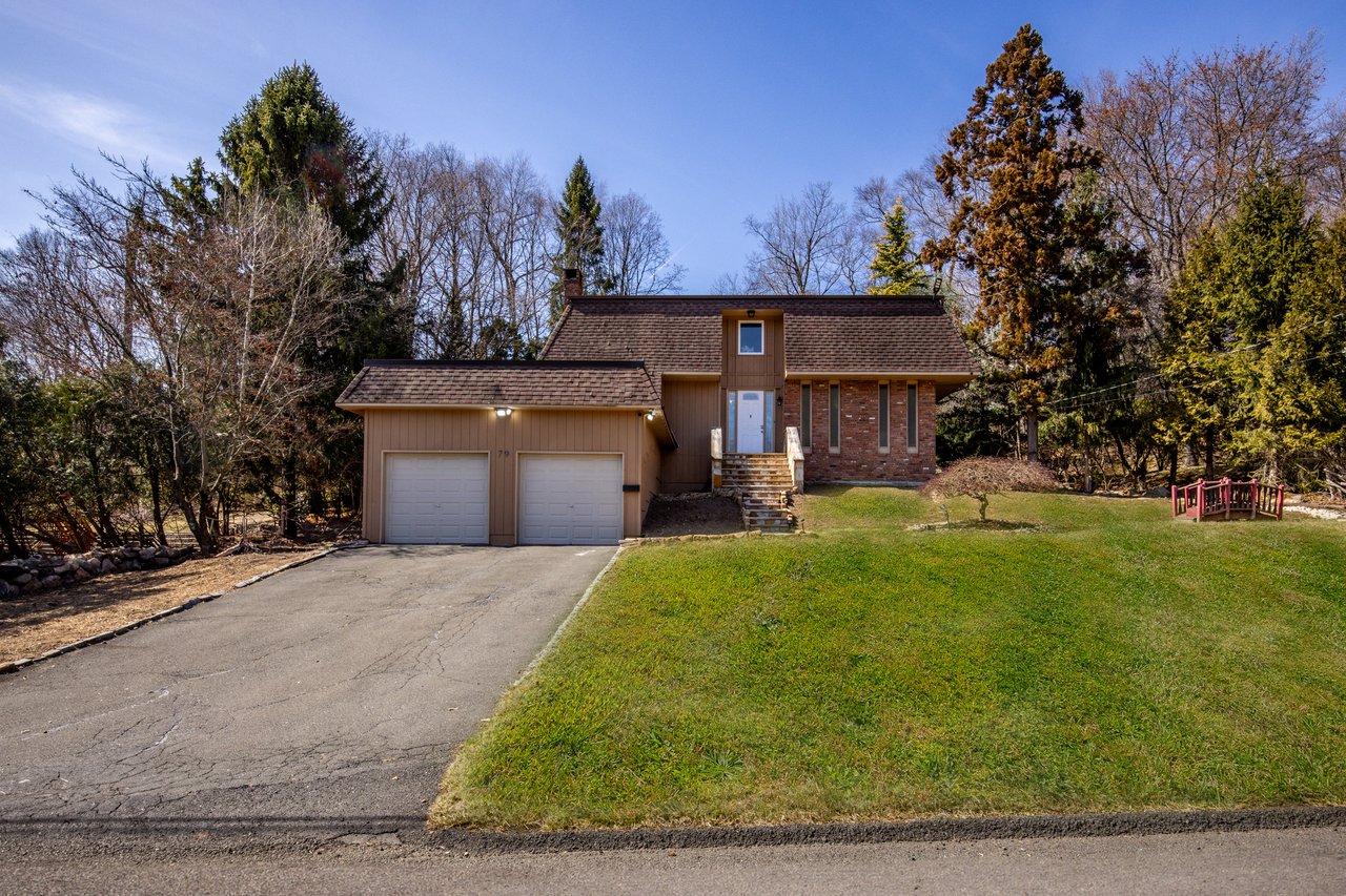 View of front of property featuring a shingled roof, driveway, a front yard, and mansard roof...